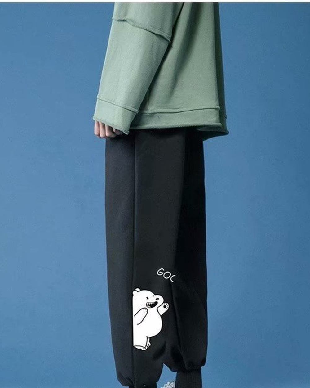 Black jogger sweatpants from the side, showing the bear peeking around the edge of the lower leg