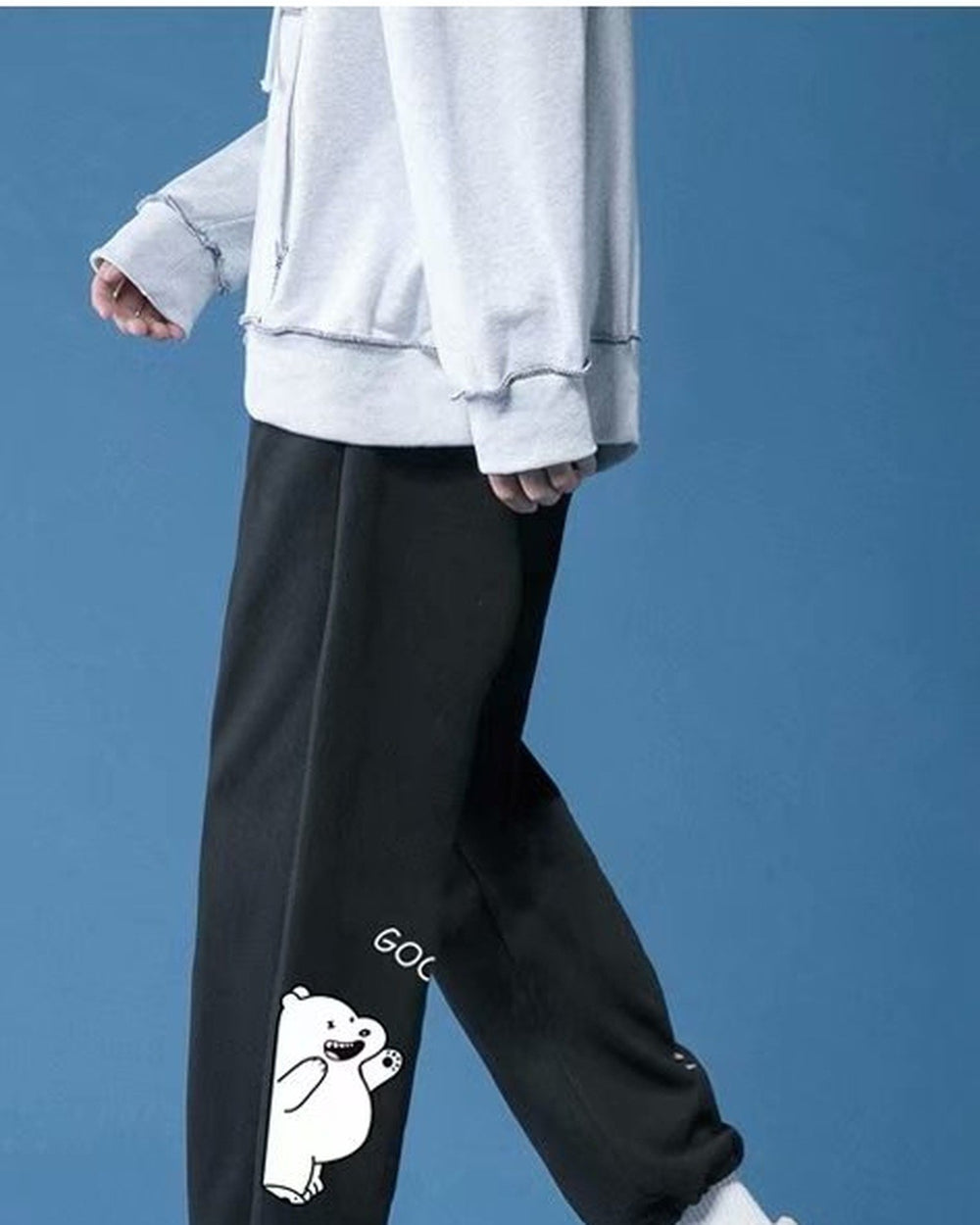 Black jogger sweatpants in motion, showing the white bear and the gathered ankle cuff