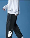 Black jogger sweatpants in motion, showing the white bear and the gathered ankle cuff