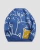 Blue knit sweater covered in white line-drawn cat faces with one yellow cat at the lower right, front view