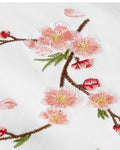 Close-up of the embroidered cherry-blossom sprig on white fabric