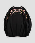 Black crew-neck sweatshirt laid flat, back with blossom branches across the shoulders