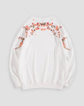 White crew-neck sweatshirt laid flat, back with blossom branches across the shoulders