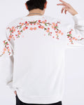 White loose sweatshirt, back view with pink cherry-blossom branches embroidered across the shoulders