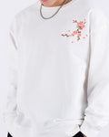 White loose sweatshirt worn with a cap, front view with the chest sprig