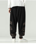 Black lantern pants with gold cloud embroidery on the lower legs and a knotted sash, worn with a white shirt