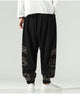 Black lantern pants with gold cloud embroidery on the lower legs and a knotted sash, worn with a white shirt