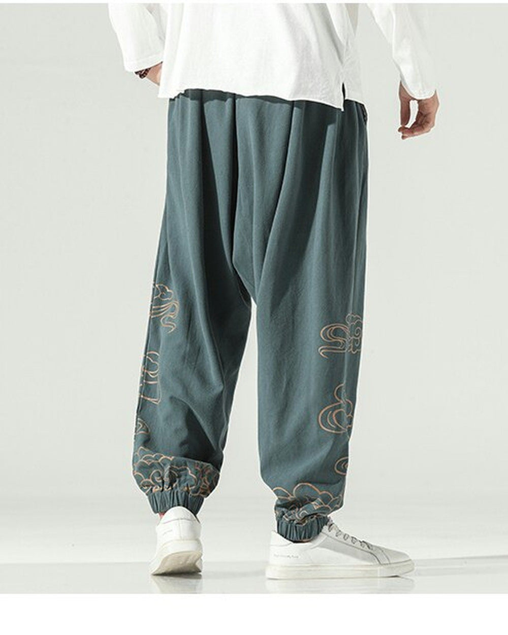 Gray green lantern pants with gold cloud embroidery on the lower legs and a knotted sash, worn with a white shirt