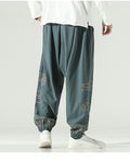 Gray green lantern pants with gold cloud embroidery on the lower legs and a knotted sash, worn with a white shirt