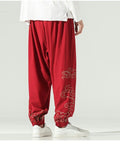 Red lantern pants with gold cloud embroidery on the lower legs and a knotted sash, worn with a white shirt
