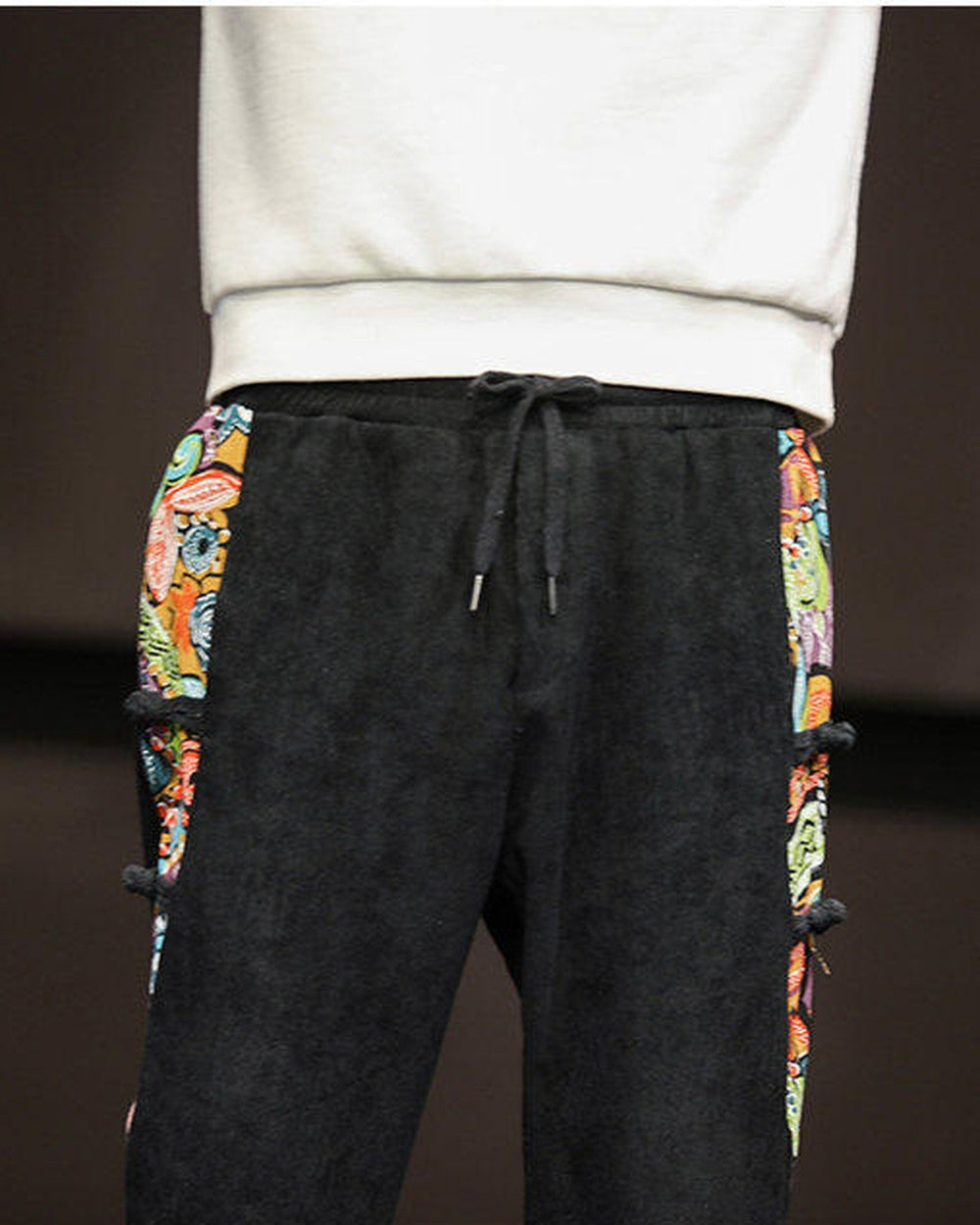 Close-up of the elastic waist, the drawcord and the printed panels on both sides of the black corduroy joggers