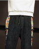 Close-up of the elastic waist, the drawcord and the printed panels on both sides of the black corduroy joggers