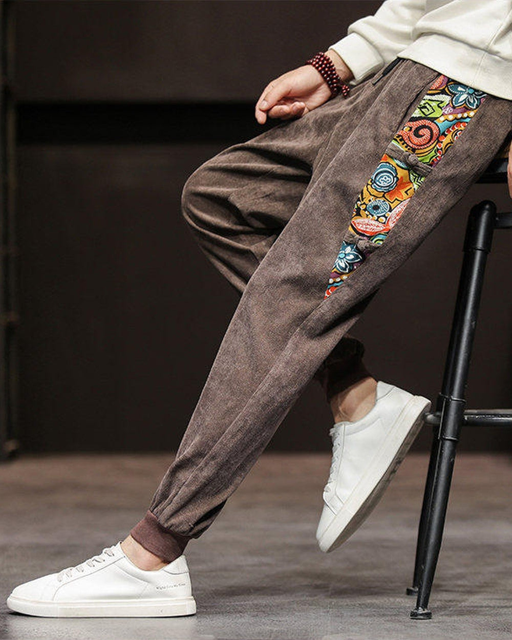 Side view of the brown corduroy joggers showing the long printed panel with frog-button knots on the outer seam