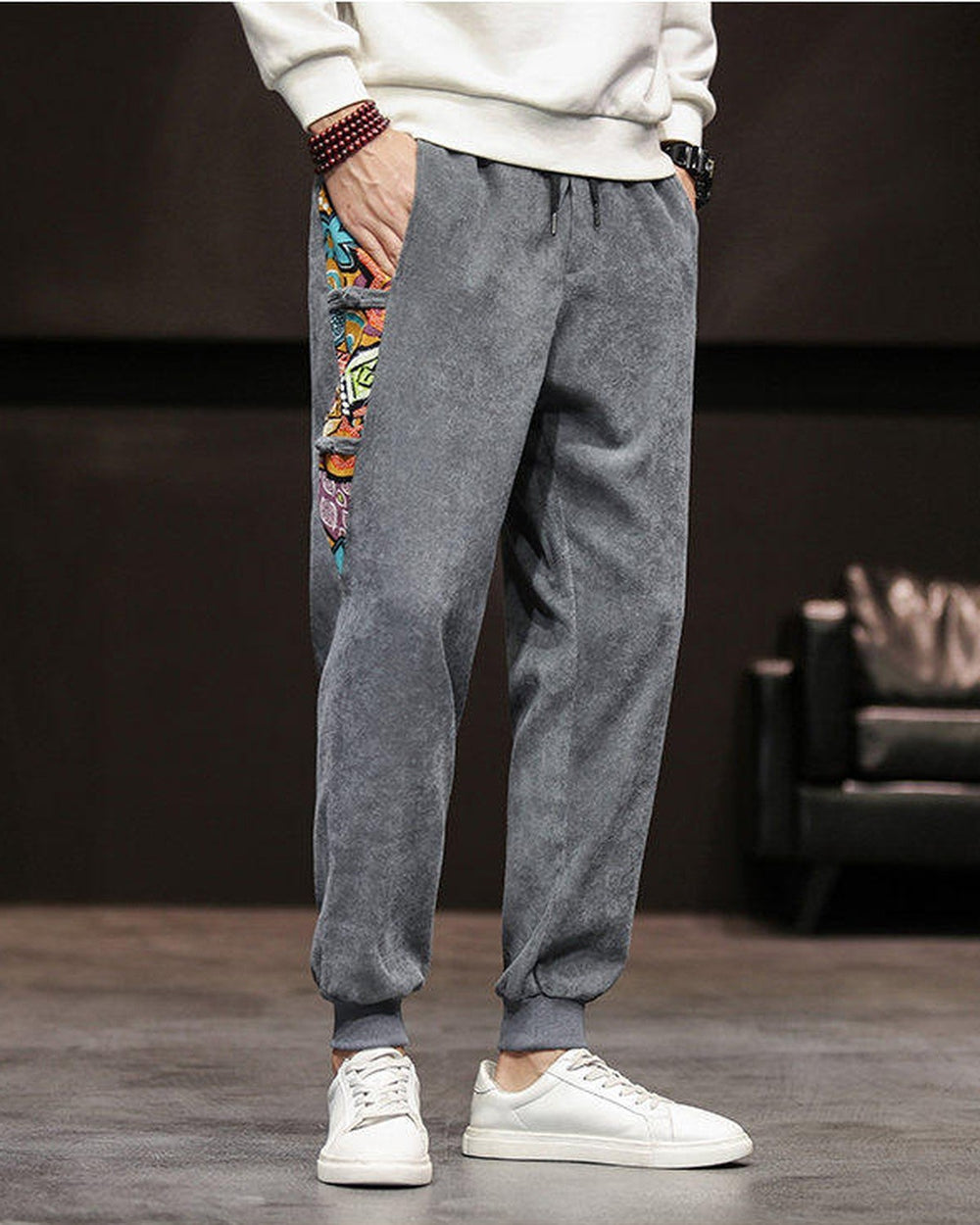 Slate gray corduroy joggers with a printed side panel and ribbed cuffs, worn with a white sweatshirt and white sneakers