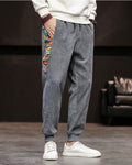 Slate gray corduroy joggers with a printed side panel and ribbed cuffs, worn with a white sweatshirt and white sneakers
