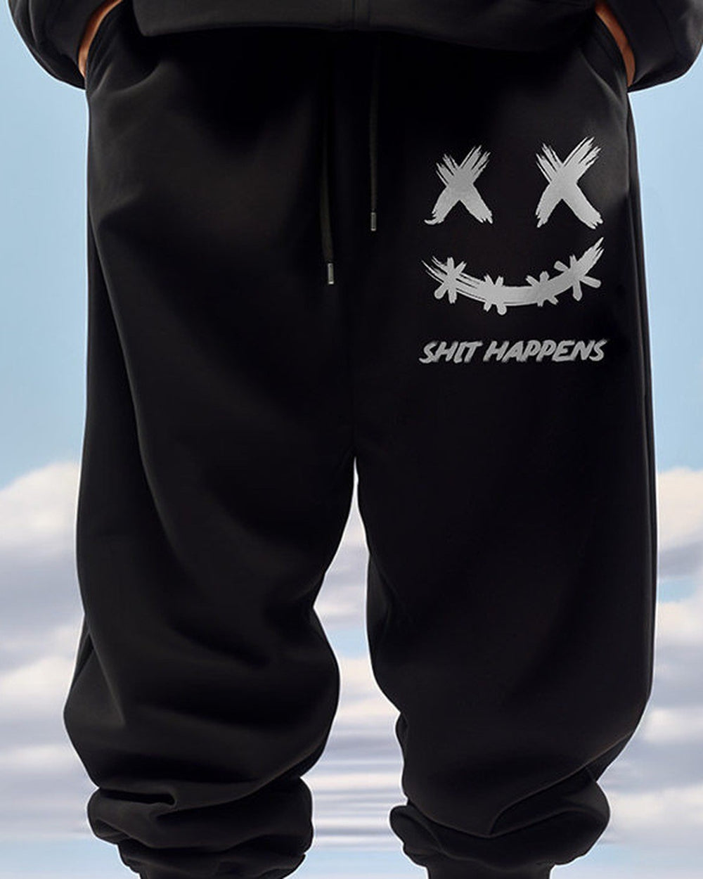 Black jogger pants with a white smiley print on the thigh, worn standing, waist to shin