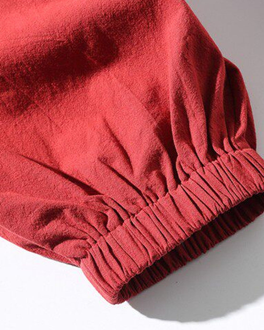 Close-up of the elastic gathered cuff on the red jogger pants