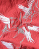 Close-up of the white-and-silver embroidered cranes on the red cotton-linen fabric