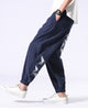 Navy crane-embroidered jogger pants in motion, with the white cranes and the elastic cuff in view