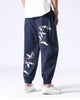 Navy crane-embroidered jogger pants seen from behind, with white cranes on the right thigh and around the left calf