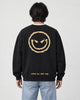 Model seen from behind in the black crewneck sweatshirt with a large gold devil smiley and SMILE ALL THE TIME at the hem