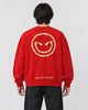 Model seen from behind in the red crewneck sweatshirt with a large gold devil smiley and SMILE ALL THE TIME at the hem