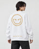 Model seen from behind at an angle in the white crewneck sweatshirt with a large gold devil smiley