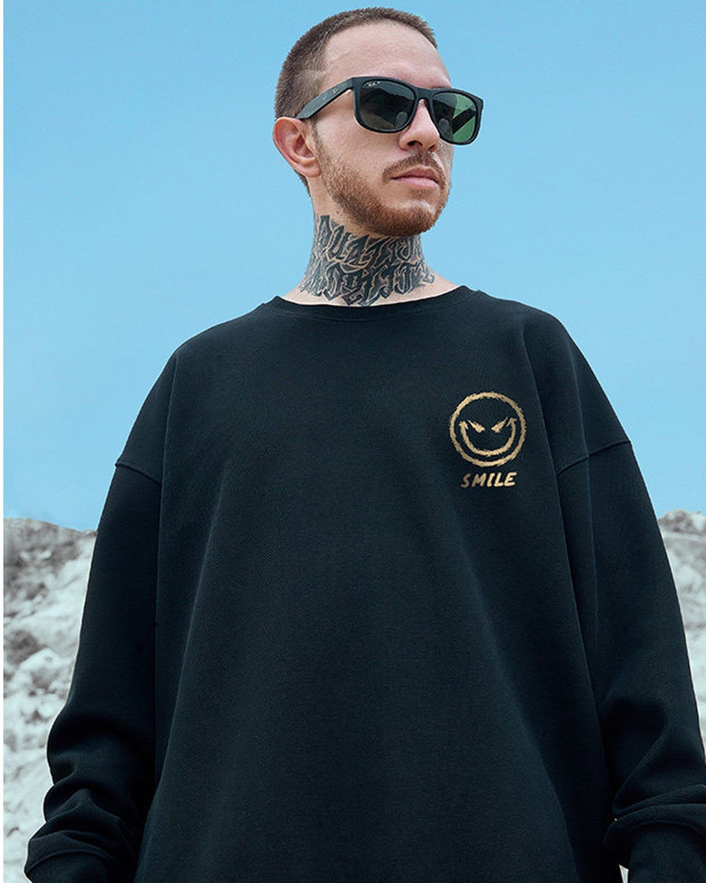 Front of the black crewneck sweatshirt with a small gold devil smiley and the word SMILE on the chest