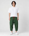 Model wearing the forest green crinkled harem pants with a white tee and white sneakers, front view