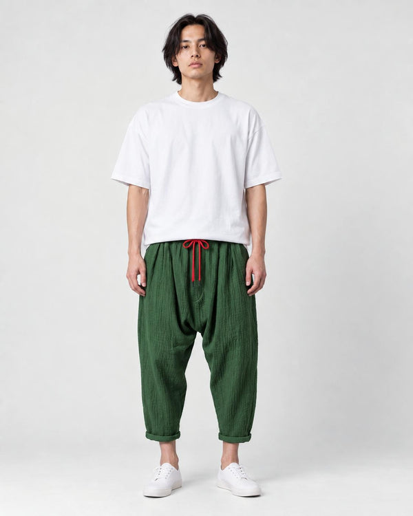 Model wearing the forest green crinkled harem pants with a white tee and white sneakers, front view