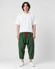 Model wearing the forest green crinkled harem pants with a white tee and white sneakers, front view