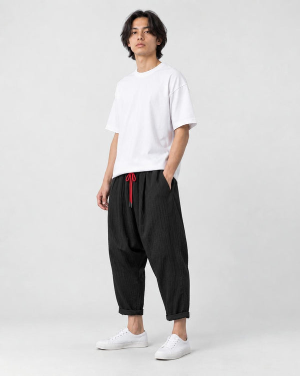 Model wearing the black crinkled harem pants with a white tee and white sneakers, three-quarter view