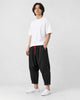 Model wearing the black crinkled harem pants with a white tee and white sneakers, three-quarter view