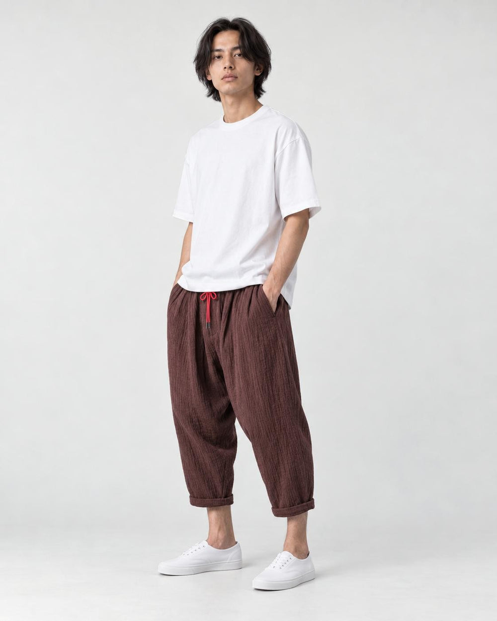 Model wearing the coffee brown crinkled harem pants with a white tee and white sneakers, three-quarter view