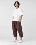 Model wearing the coffee brown crinkled harem pants with a white tee and white sneakers, three-quarter view