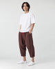 Model wearing the coffee brown crinkled harem pants with a white tee and white sneakers, three-quarter view