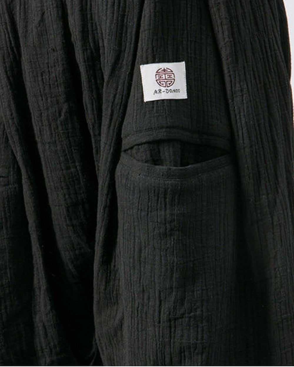 Close-up of the woven label on the back patch pocket of the black harem pants