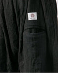 Close-up of the woven label on the back patch pocket of the black harem pants