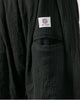 Close-up of the woven label on the back patch pocket of the black harem pants