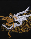 Close view of the small gold and white dragon head embroidered on the left chest of the black sweatshirt