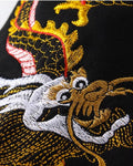 Close view of the dragon's head and white clouds embroidered near the cuff of the black sweatshirt sleeve