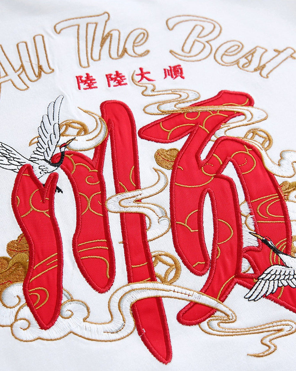Close-up of the red character, white crane and gold-thread script embroidered on the back of the white T-shirt