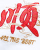 Close-up of the small red character and gold ALL THE BEST lettering embroidered on the chest of the white T-shirt
