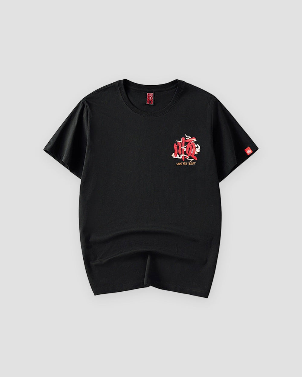 Front of the black T-shirt with a small red embroidered emblem on the left chest and a red tag on the sleeve