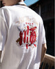 Man seen from behind in the white T-shirt, showing the red and gold embroidery across the upper back