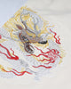 Close-up of the embroidered dragon in gray, silver and gold thread with red flames on the cream leg