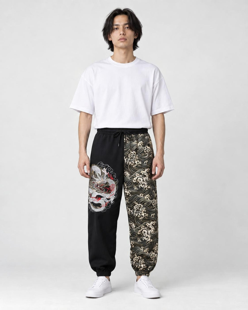 Model wearing the black and wave-print jogger pants with a white tee and white sneakers, front view