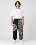 Model wearing the black and wave-print jogger pants with a white tee and white sneakers, front view