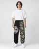 Model wearing the black and wave-print jogger pants with a white tee and white sneakers, front view