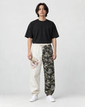 Model wearing the cream and wave-print jogger pants with a black tee and white sneakers, front view